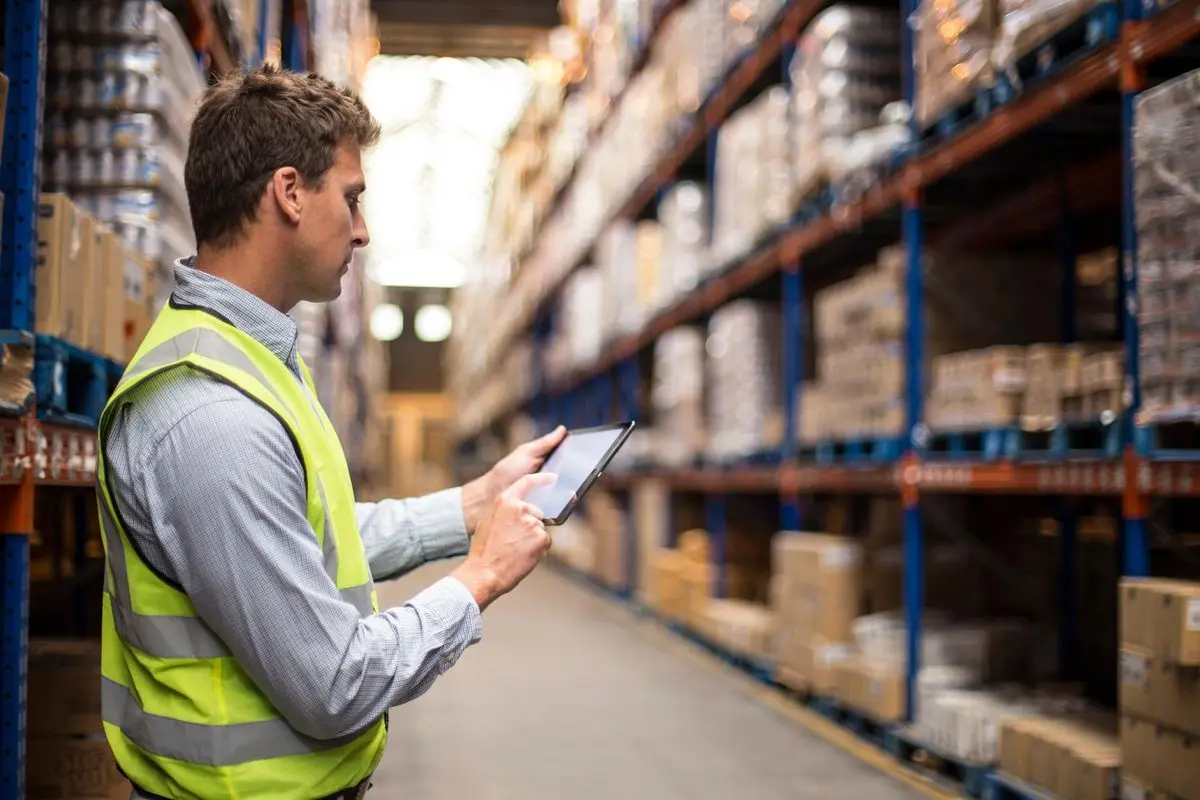 Specialist checking goods between warehouse racks